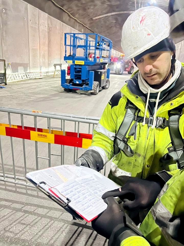 Montör i hjälm och varselkläder går igenom checklista i tunnel